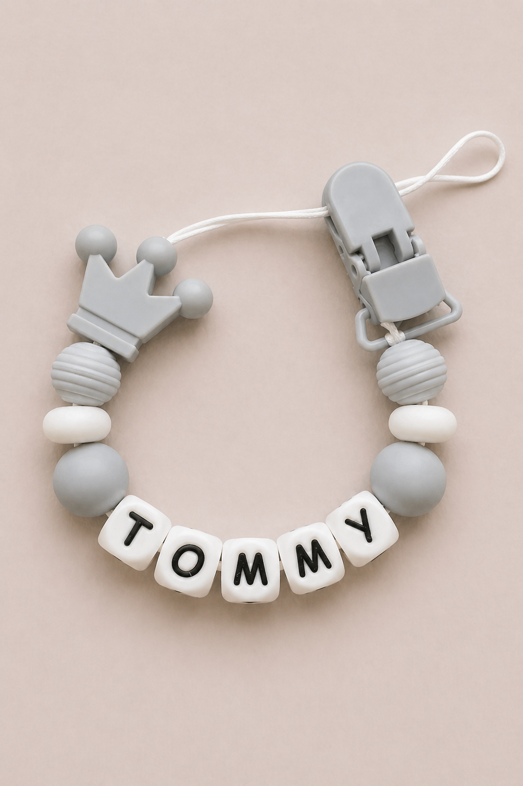 Teething ring with 'Tommy' name tag on a beige background