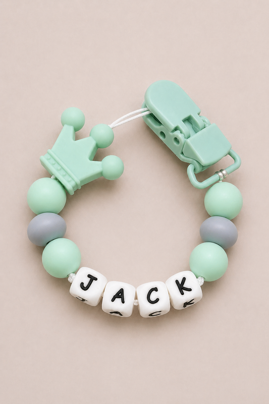Mint green baby teether with 'JACK' on a beige background