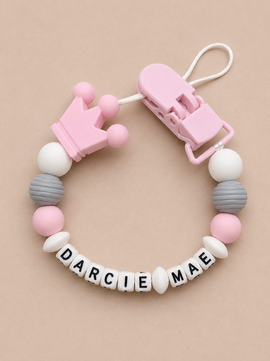 Baby teether with colorful beads and a clip on a beige background