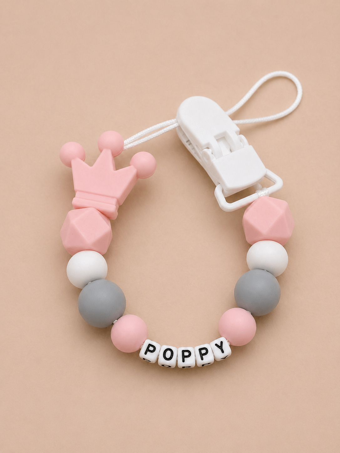 Baby teether with colorful beads and 'POPPY' label on a beige background
