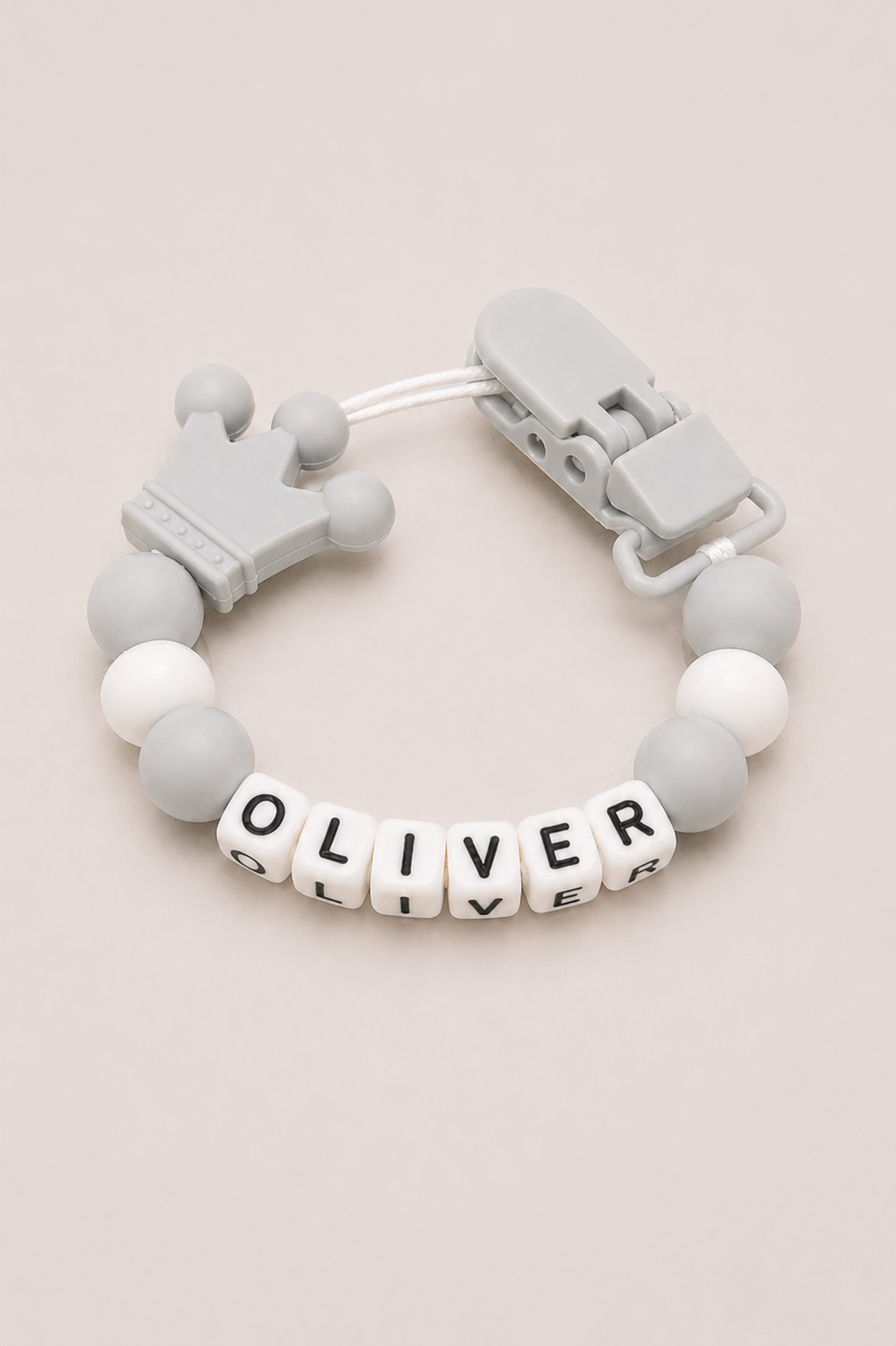 Gray and white teething bracelet with 'OLIVER' on a beige background