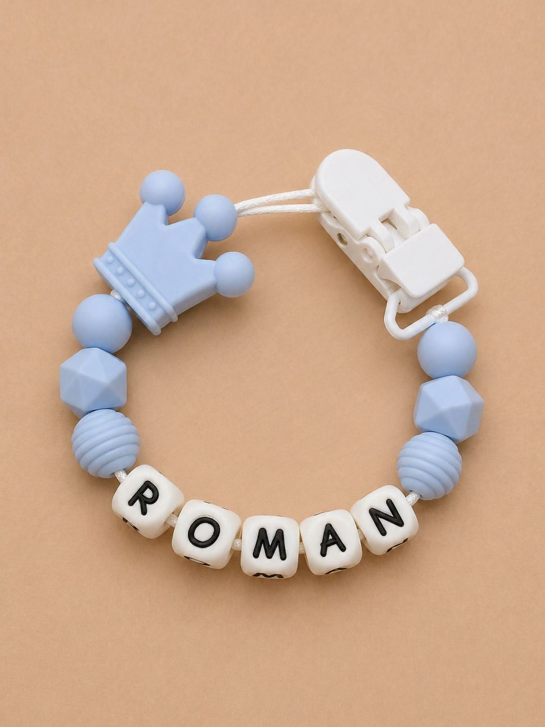 Baby teether with 'ROMAN' name on a beige background