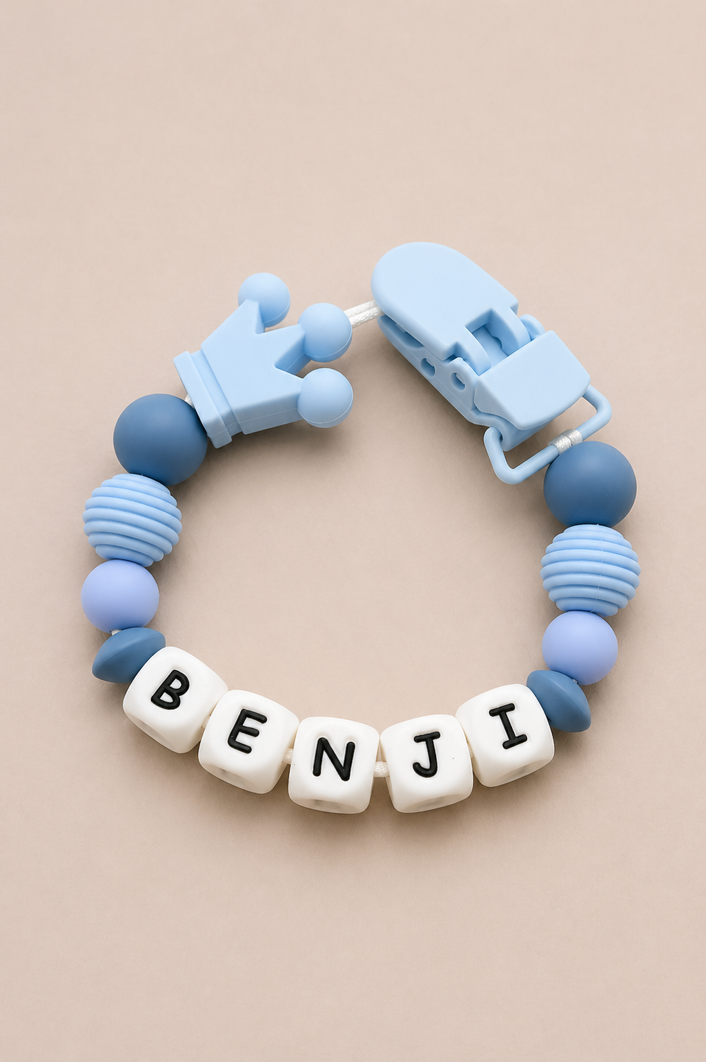 Blue baby teether with 'BENJI' beads on a beige background