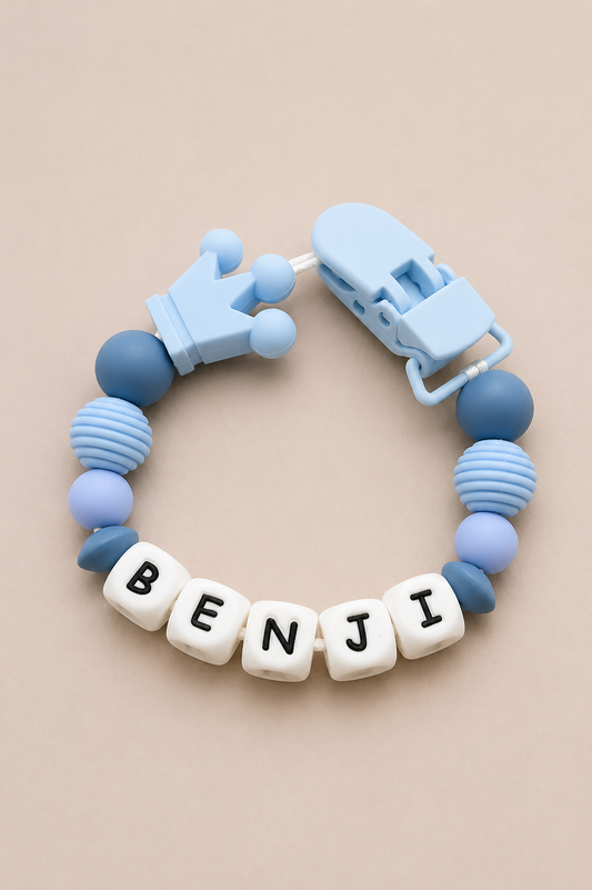 Blue baby teether with 'BENJI' beads on a beige background