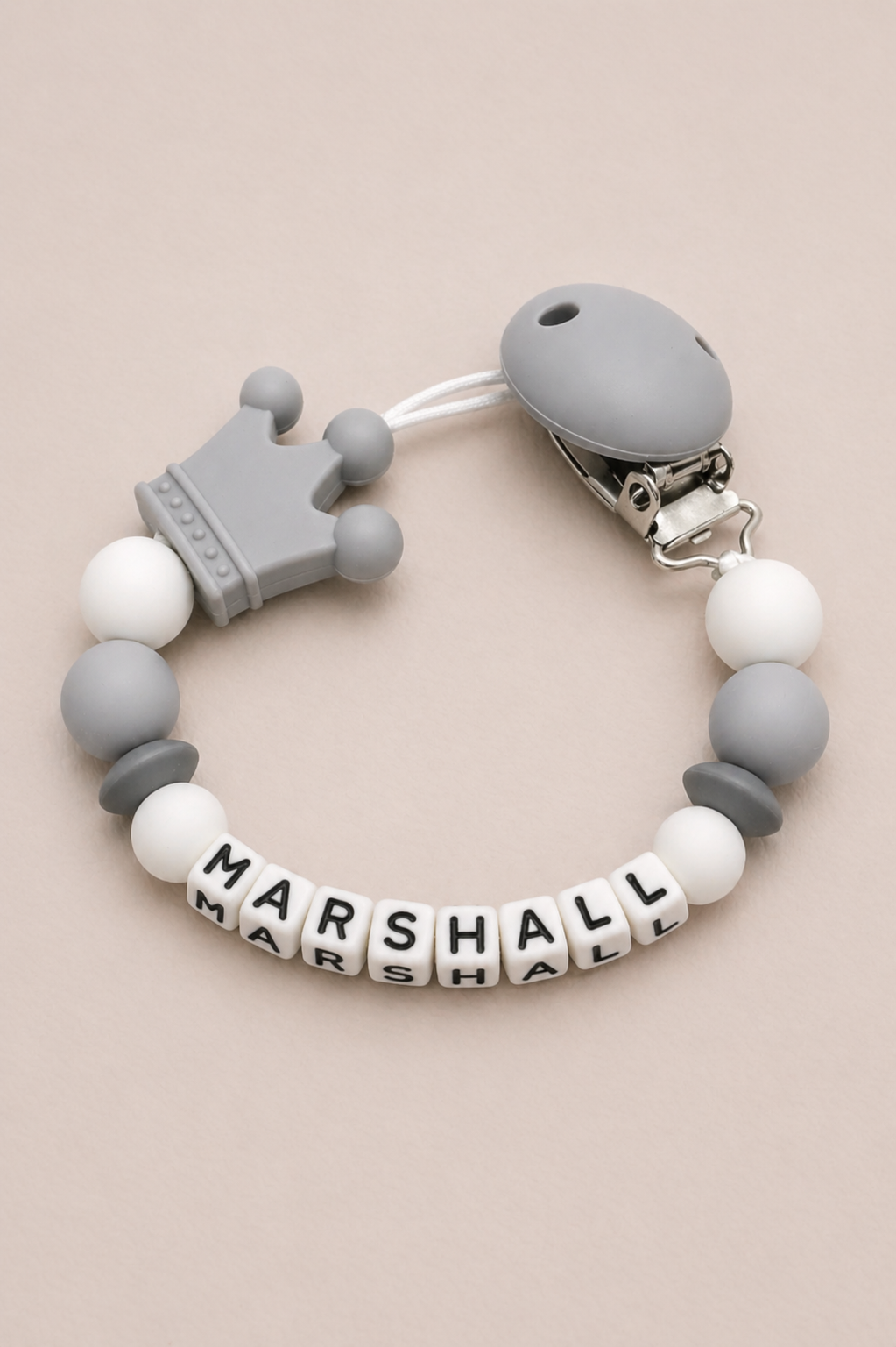 Teething bracelet with gray and white beads and a crown charm on a beige background
