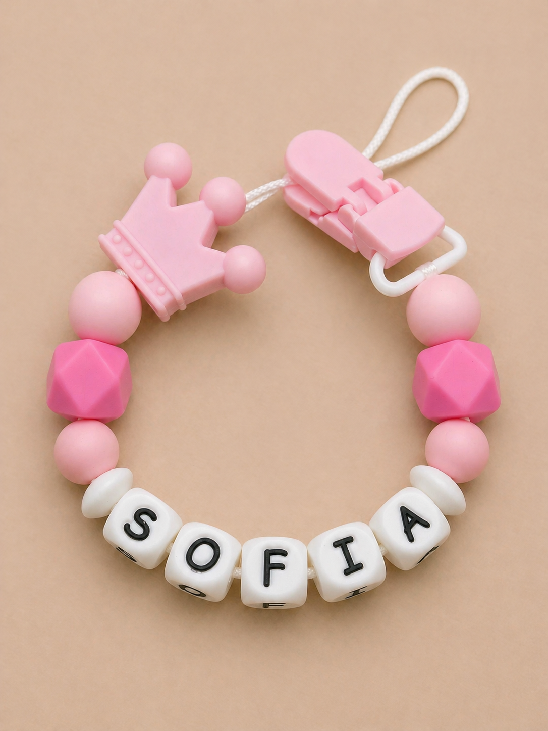 Pink and white teething necklace with 'SOFIA' on a beige background