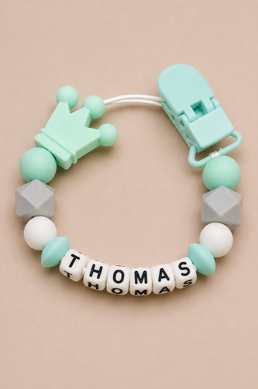 Teething ring with colorful beads and name 'THOMAS' on a beige background