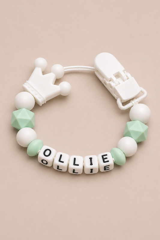 Baby teether with name 'OLLIE' on a beige background