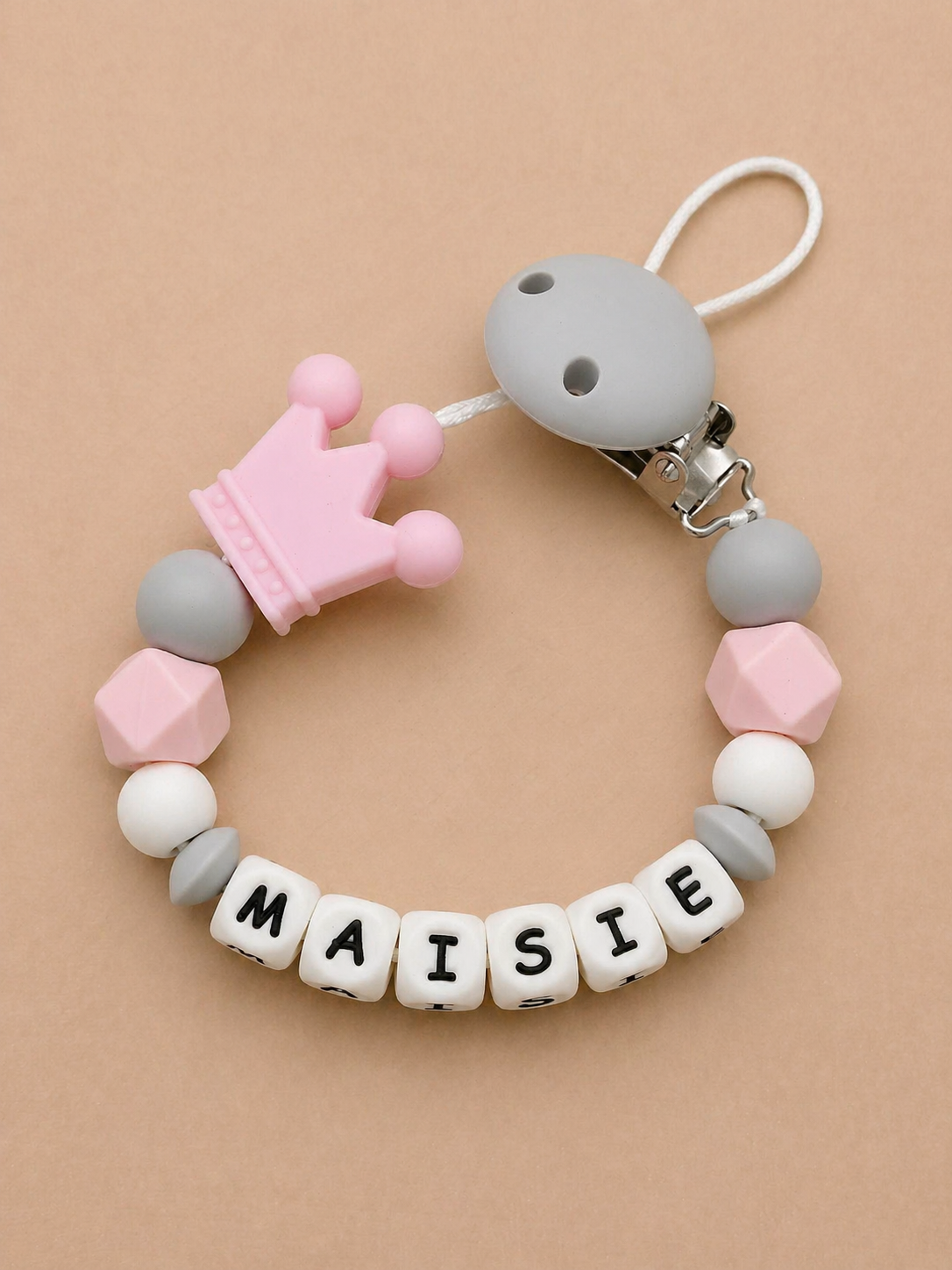Baby teether with colorful beads and 'MAISIE' name on a beige background