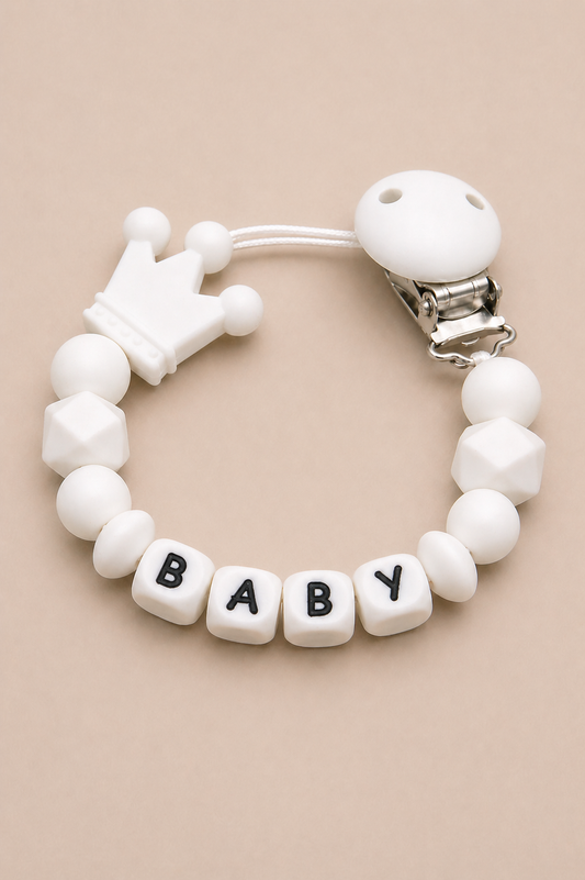 White baby teether with 'BABY' beads on a beige background
