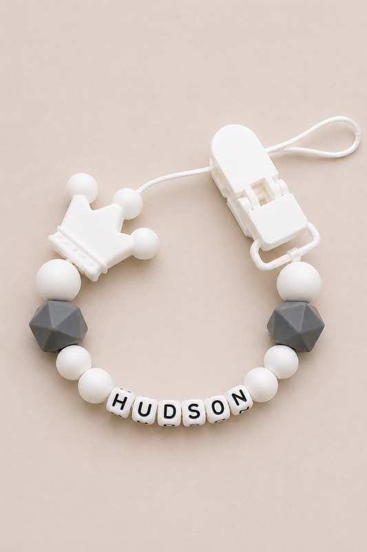 Teething necklace with crown and geometric beads on a beige background