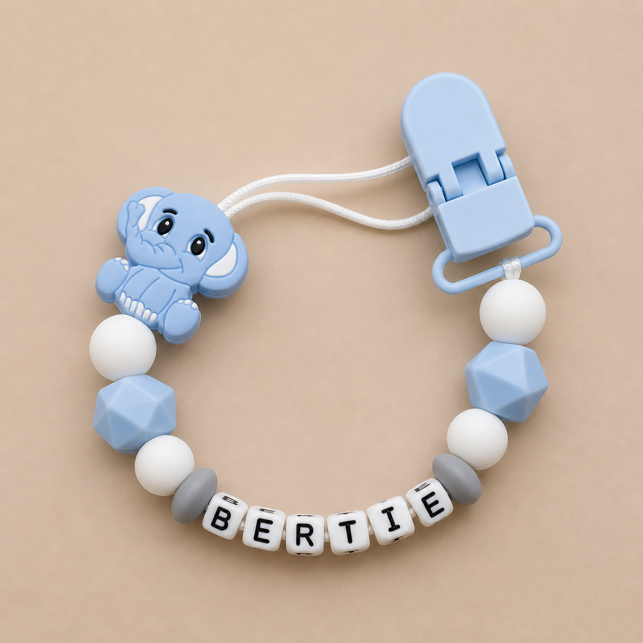 Baby dummy clip with elephant design and 'BERTIE' beads on a beige background
