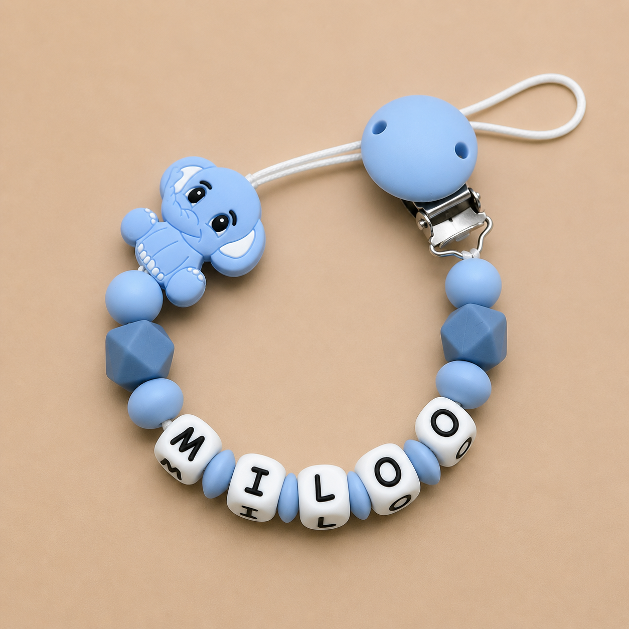 Blue silicone dummy clip with letter beads on a beige background