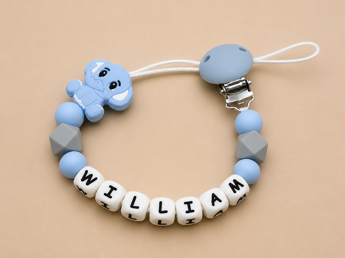 Baby dummy clip with name 'William' on a beige background