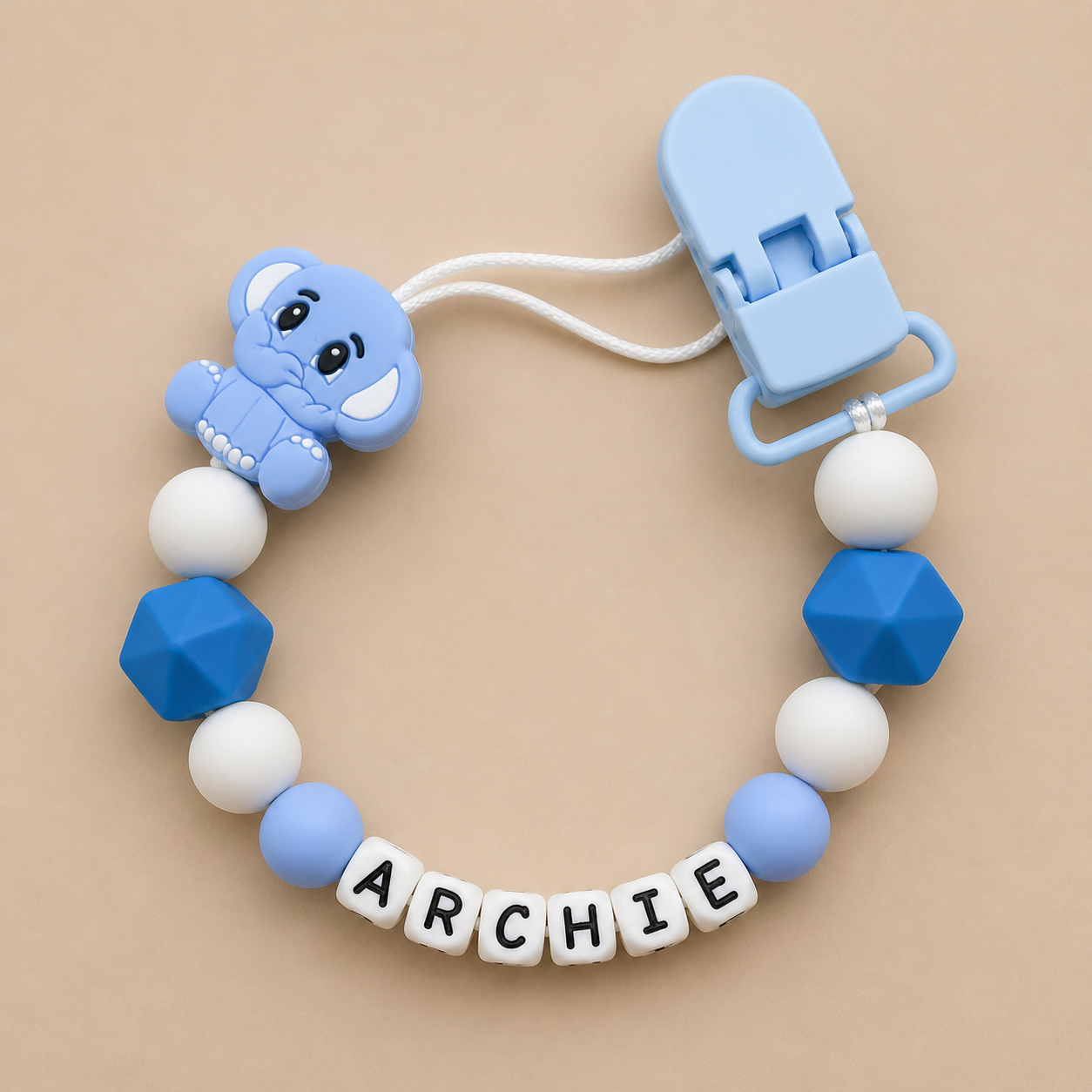 dummy clip with blue and white beads and a clip on a beige background