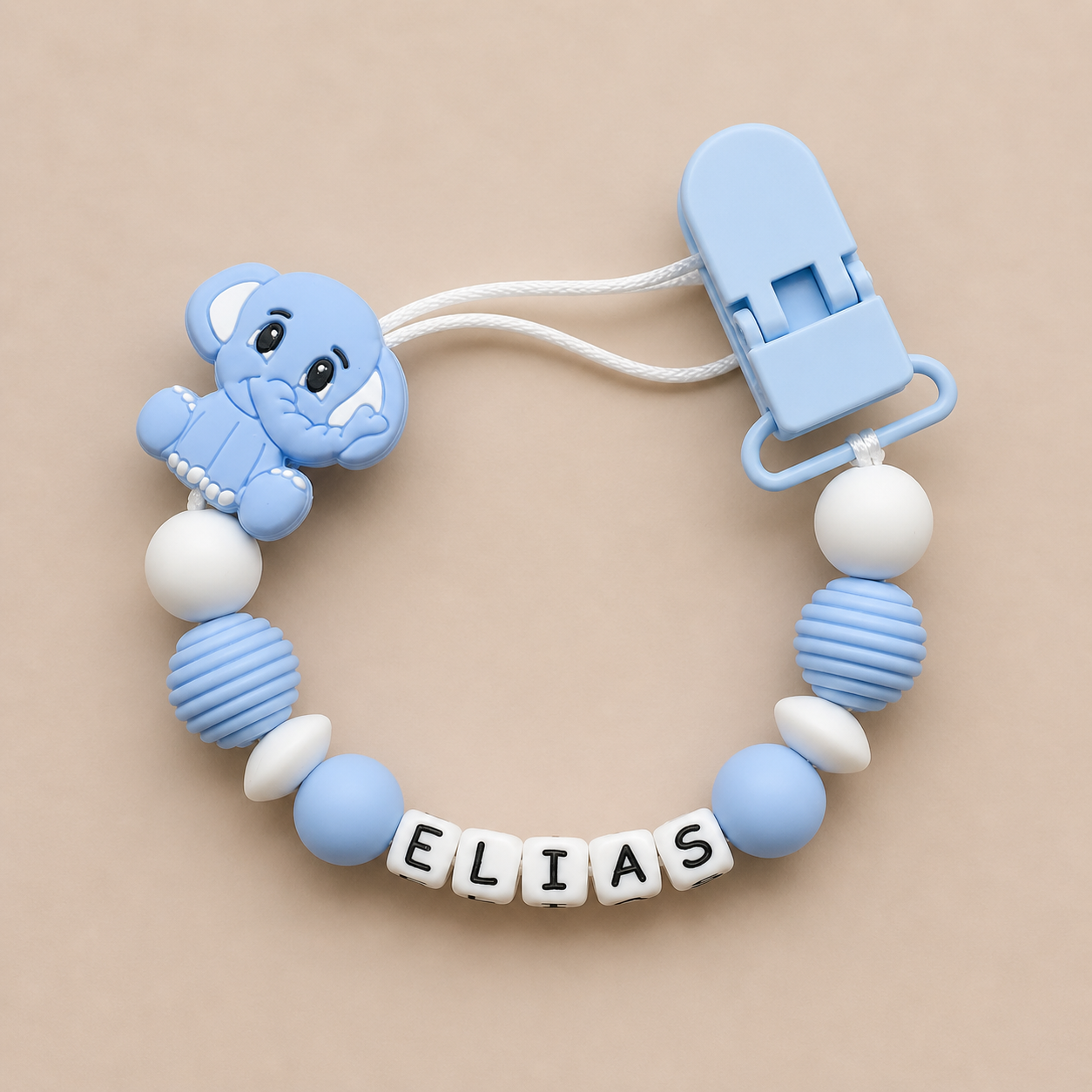 Blue elephant dummy clip with 'ELIAS' on a beige background