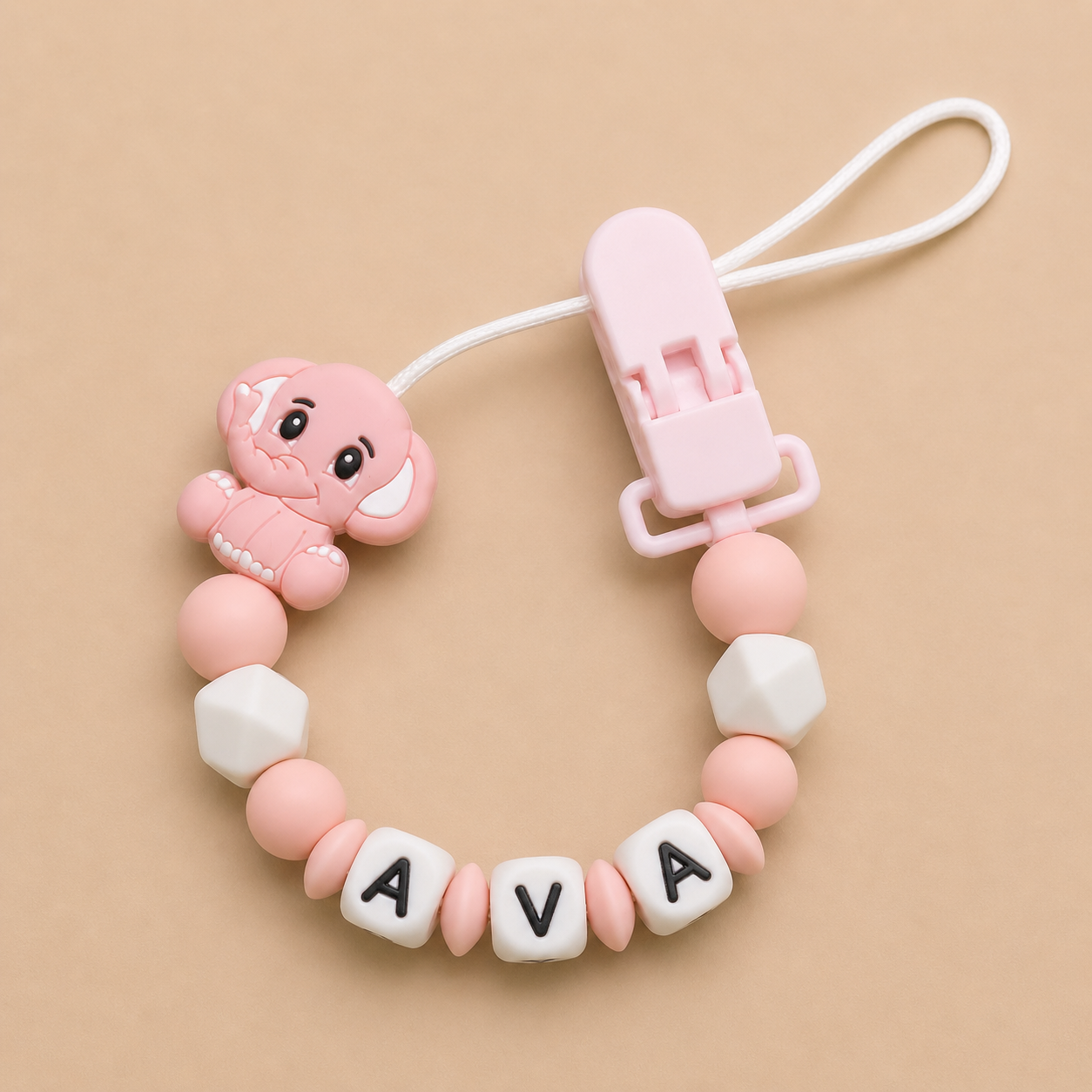 Pink baby dummy clip with 'AVA' beads on a beige background