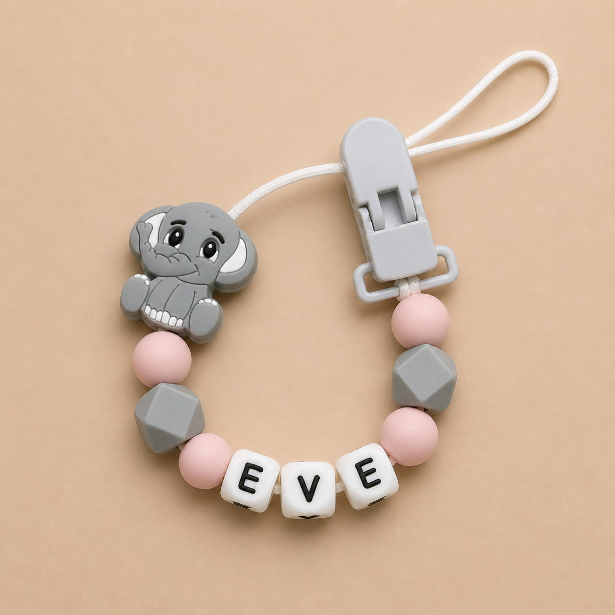 dummy clip with elephant charm and 'EVE' beads on a beige background
