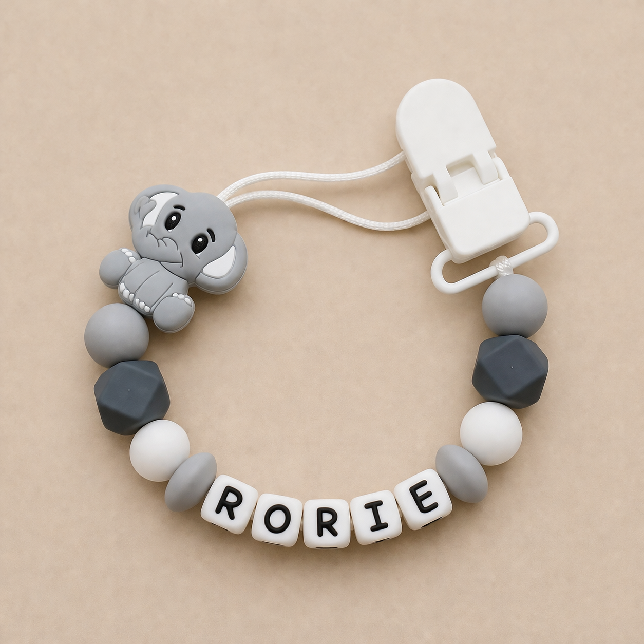 dummy clip with elephant design and 'RORIE' beads on a beige background