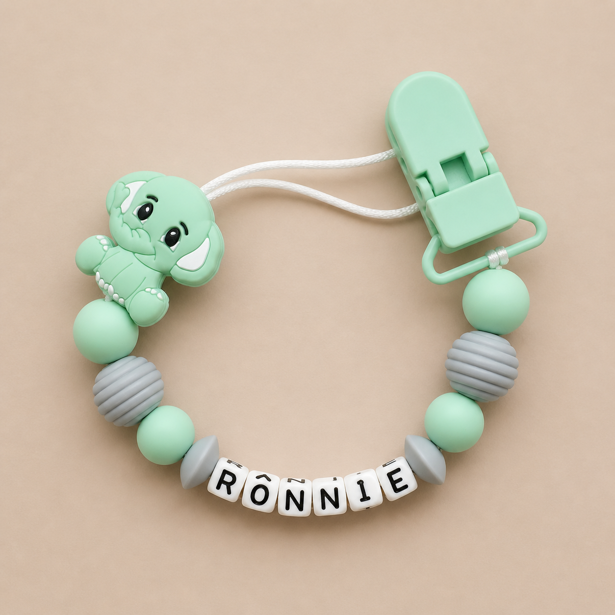 dummy clip with a teddy bear design and 'RONNIE' name on a beige background