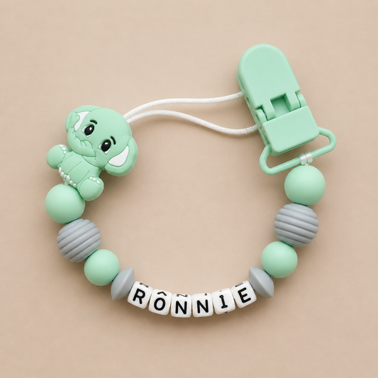 dummy clip with a teddy bear design and 'RONNIE' name on a beige background