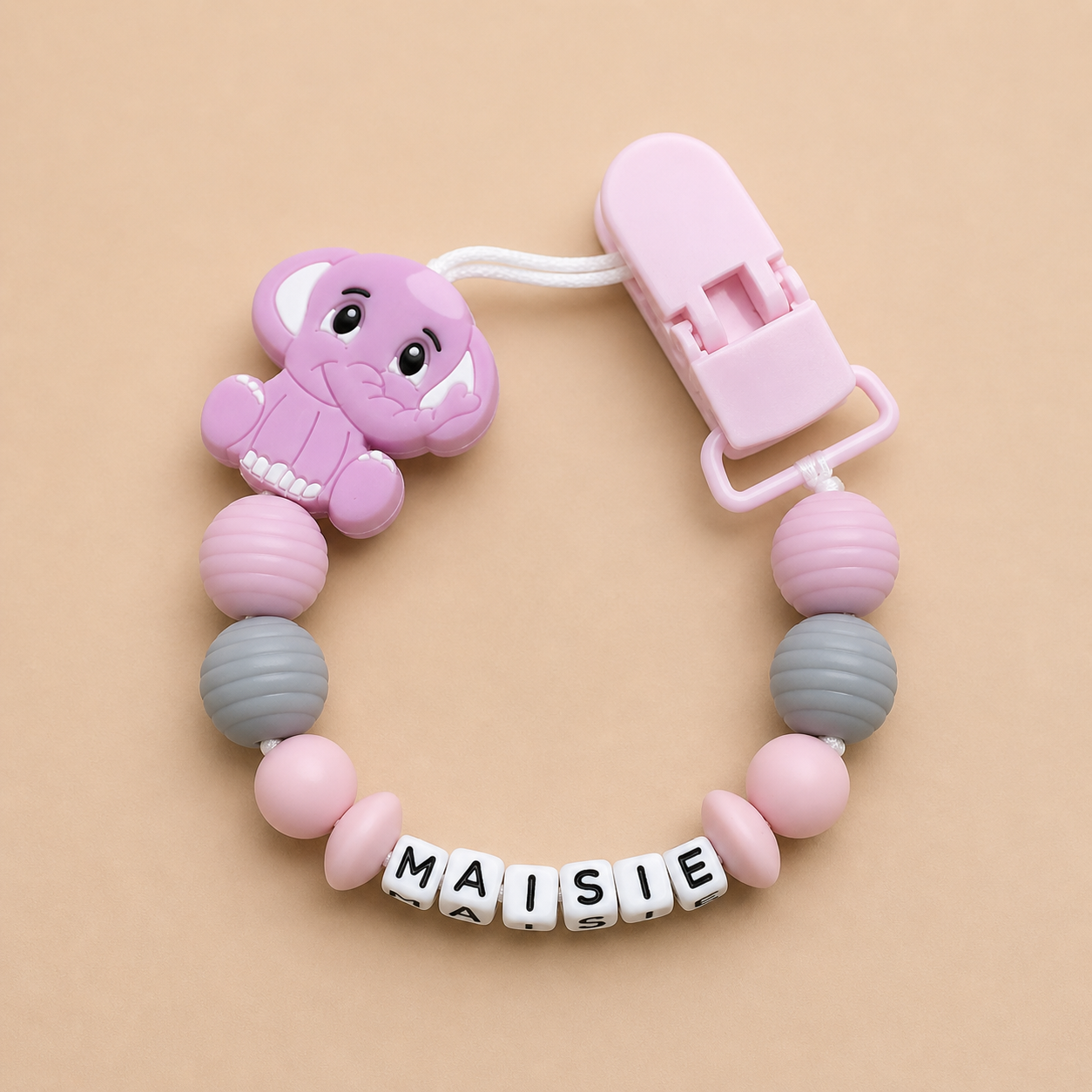 Baby dummy clip with colorful beads and a pink clip on a beige background