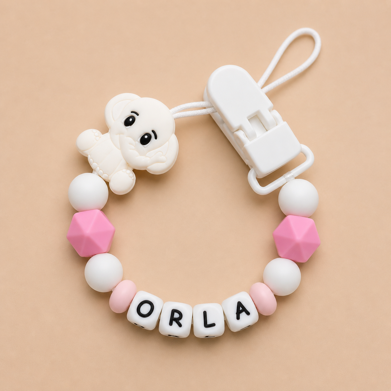 Baby dummy clip with 'ORLA' beads on a beige background