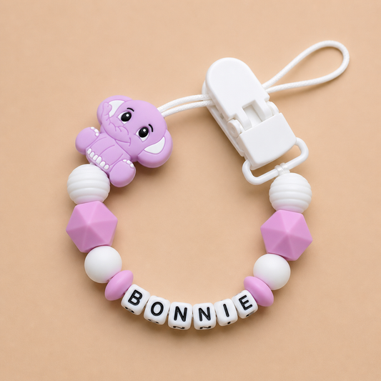 dummy clip with a purple elephant charm and 'BONNIE' letter beads on a beige background