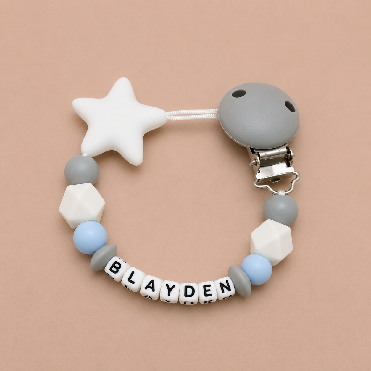 Baby dummy clip with star and geometric beads on a beige background