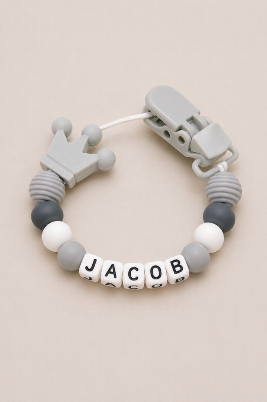 Teething bracelet with gray and white beads and a crown charm on a beige background