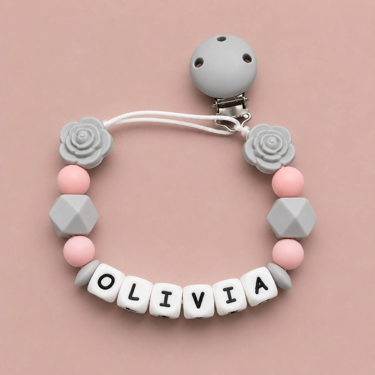Soothie clip with pink and gray beads and letter beads spelling 'OLIVIA' on a pink background