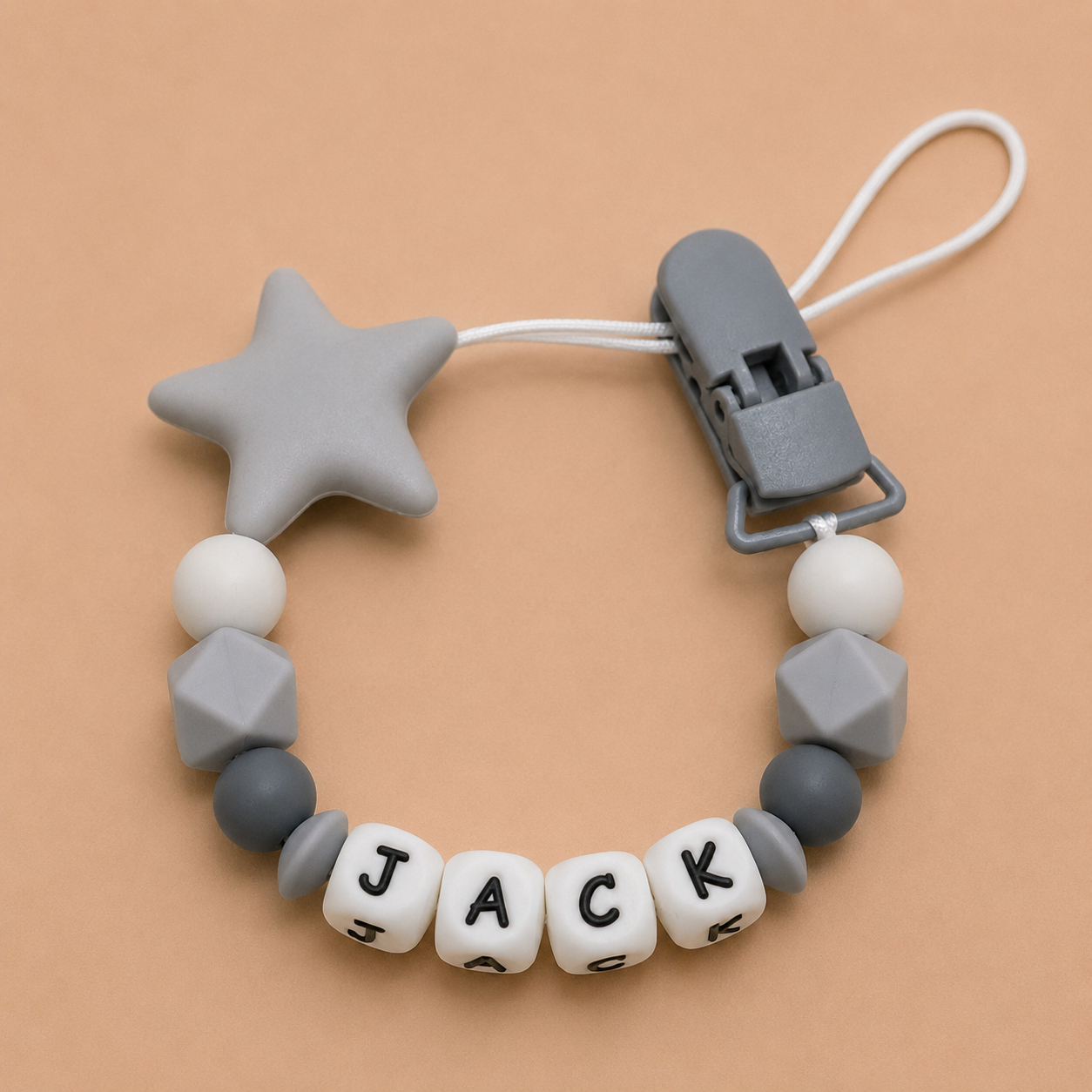 Silicone dummy clip with star and geometric shapes on a beige background