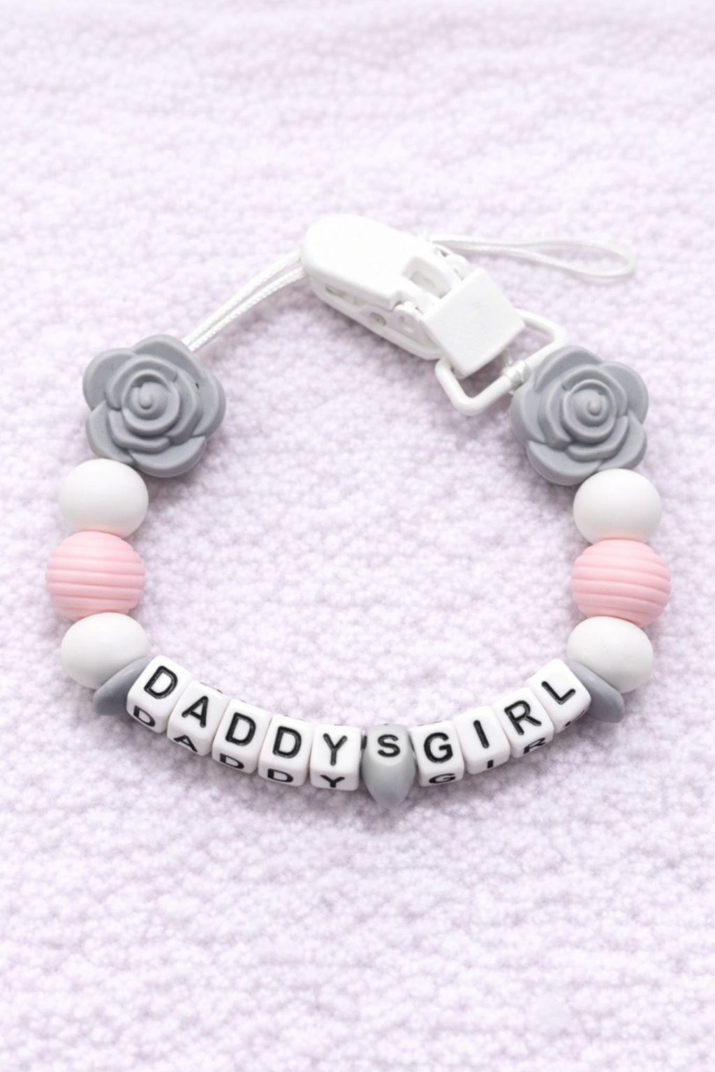 dummy chain with 'DADDY'S GIRL' beads on a textured light purple background