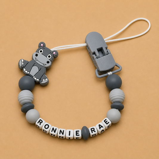 Gray hippo-shaped teether with letter beads on a beige background