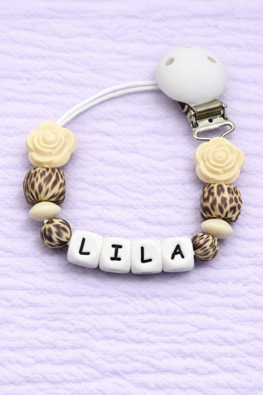 Pacifier clip with leopard print and beige beads on a purple textured background