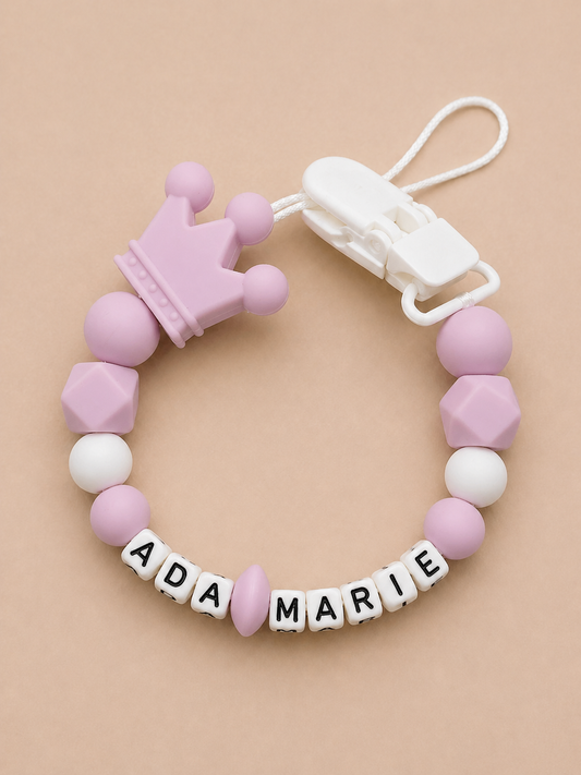 Pink and white teething ring with name beads on a beige background