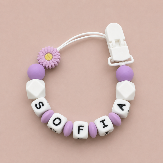 Baby Dummy Clip with 'SOFIA' beads and a flower charm on a beige background
