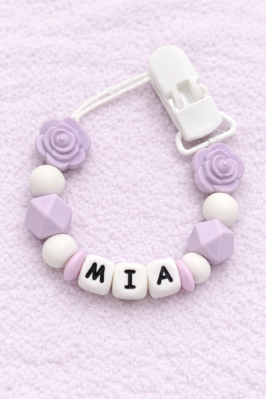 Baby dummy chain with 'MIA' name on a pink background
