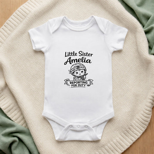 White baby onesie with 'Little Sister Amelia Reporting for Duty' text and graphic on a textured surface.