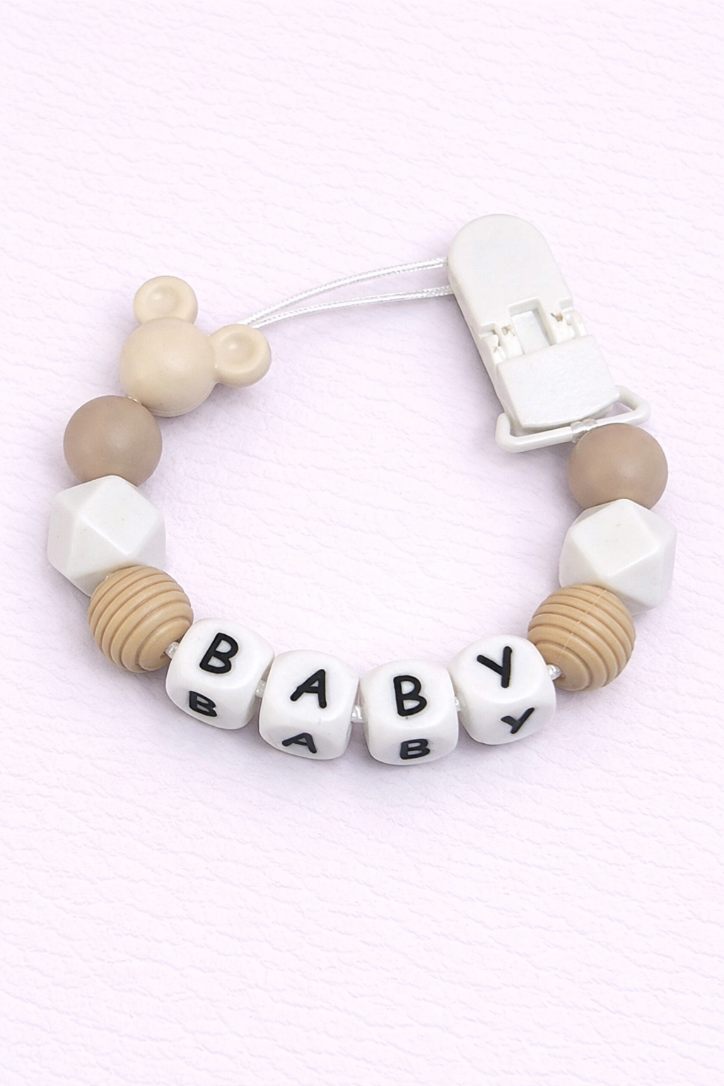 Baby dummy clip with letter beads spelling 'BABY' on a light pink background