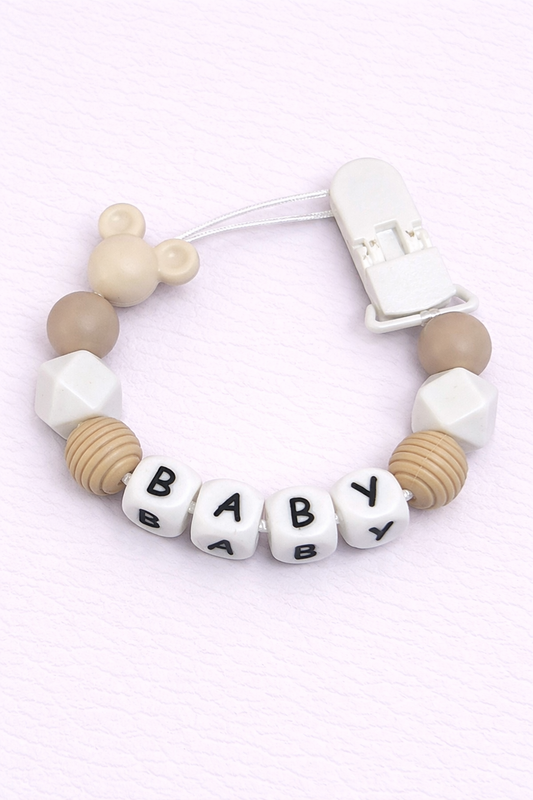 Baby dummy clip with letter beads spelling 'BABY' on a light pink background