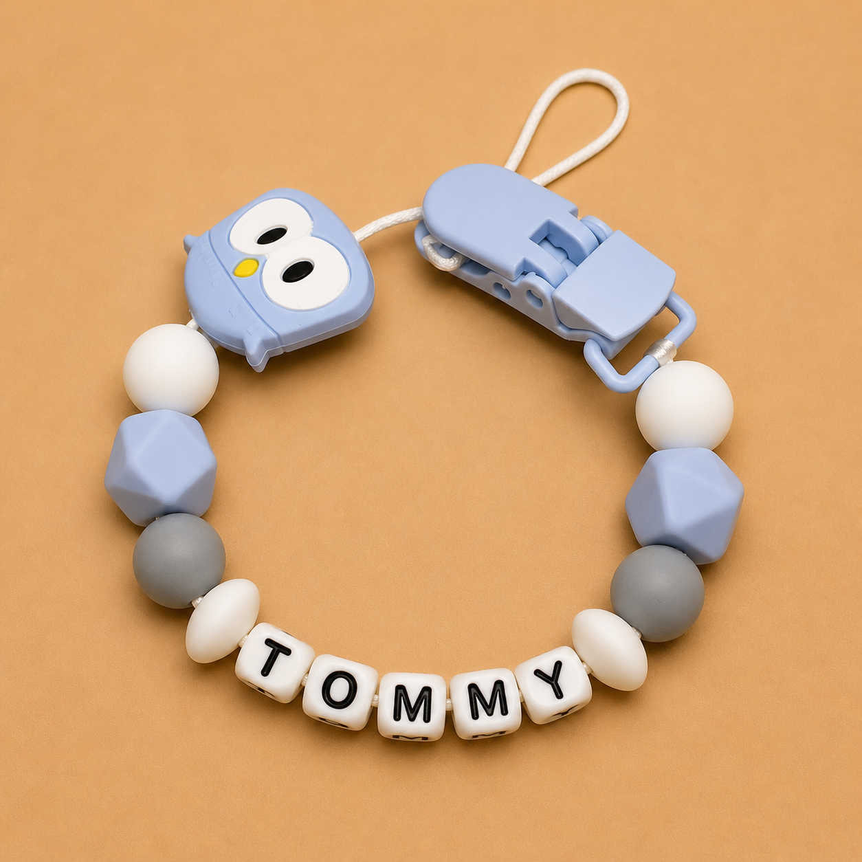 dummy clip with colorful beads and 'Tommy' nameplate on a brown background