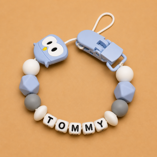 dummy clip with colorful beads and 'Tommy' nameplate on a brown background
