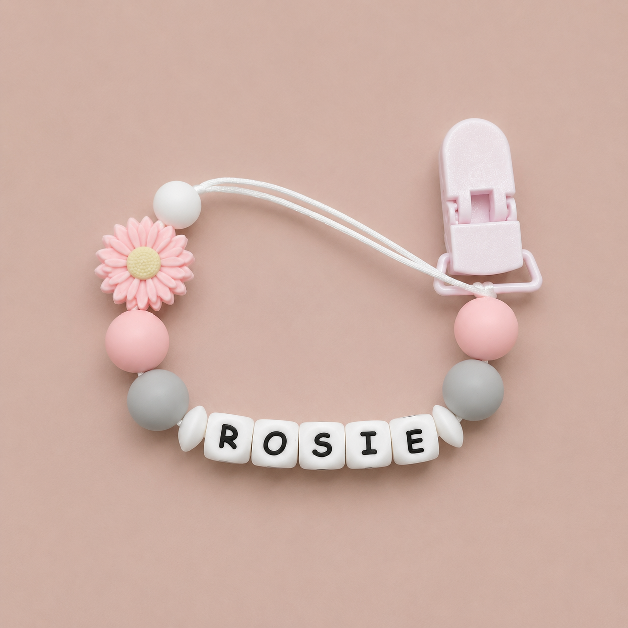 Baby dummy clip with colorful beads and a clip on a pink background
