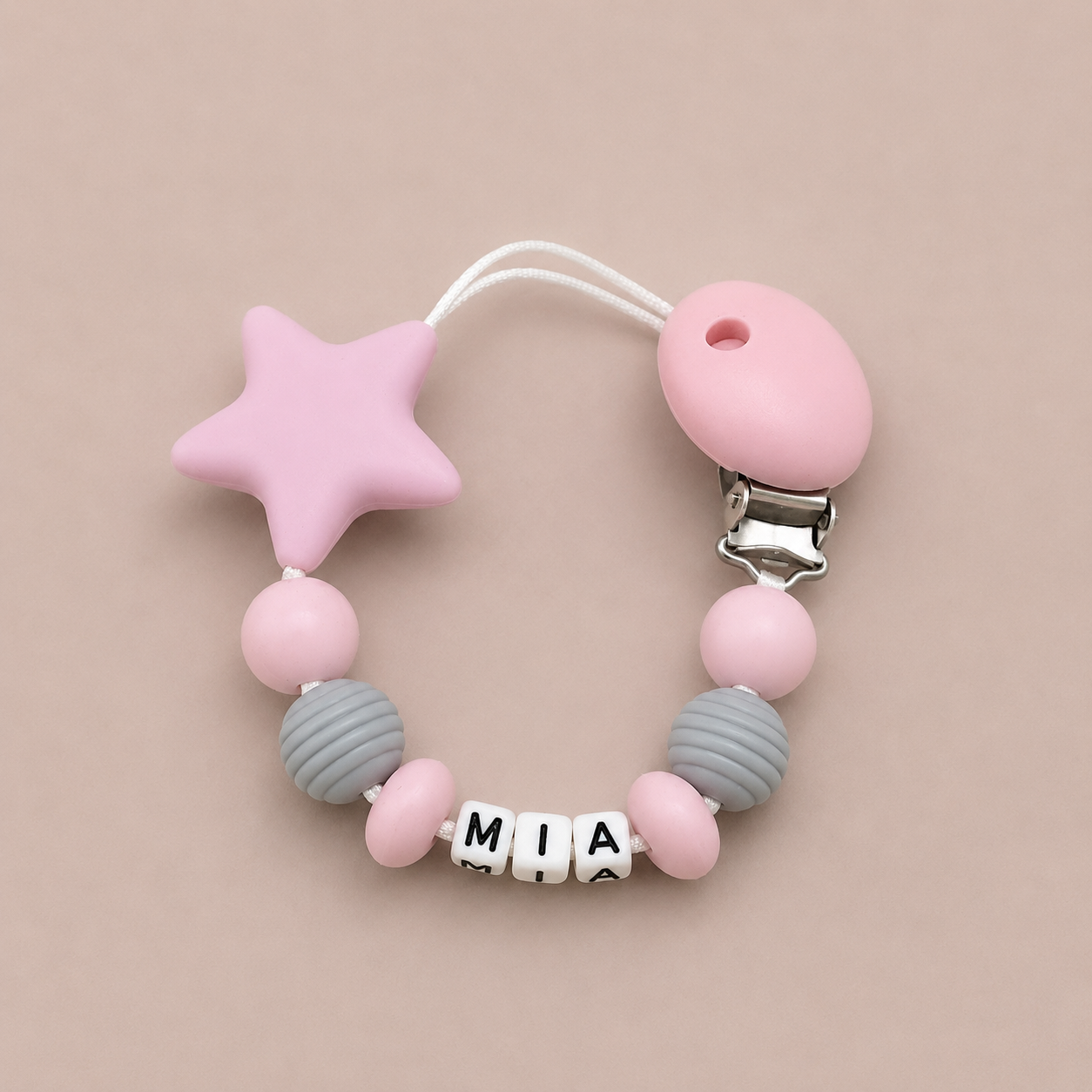 Pink and grey dummy clip with a star-shaped clip on a beige background