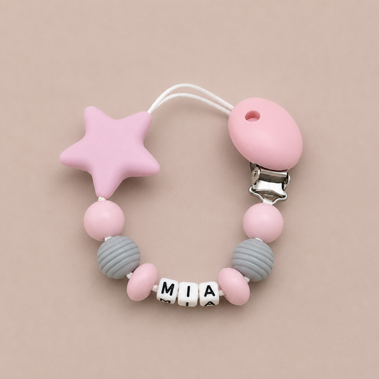 Pink and grey dummy clip with a star-shaped clip on a beige background