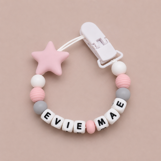 Baby dummy clip with star-shaped clip and personalized name beads on a beige background