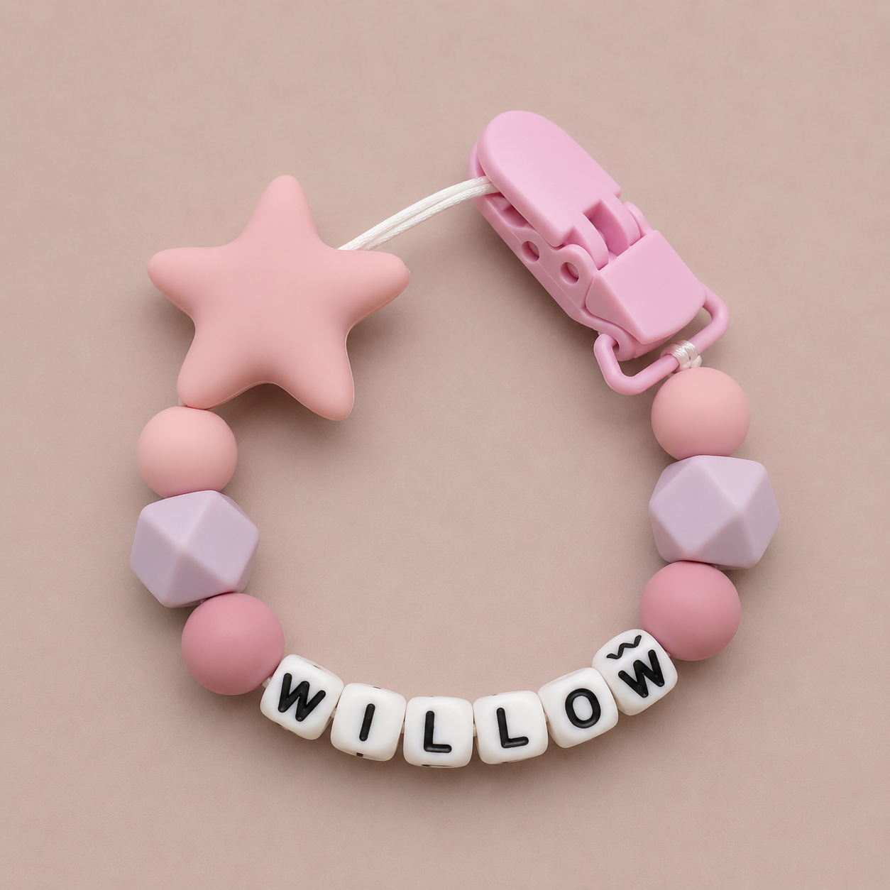 Pink and purple dummy clip with 'WILLOW' on a beige background