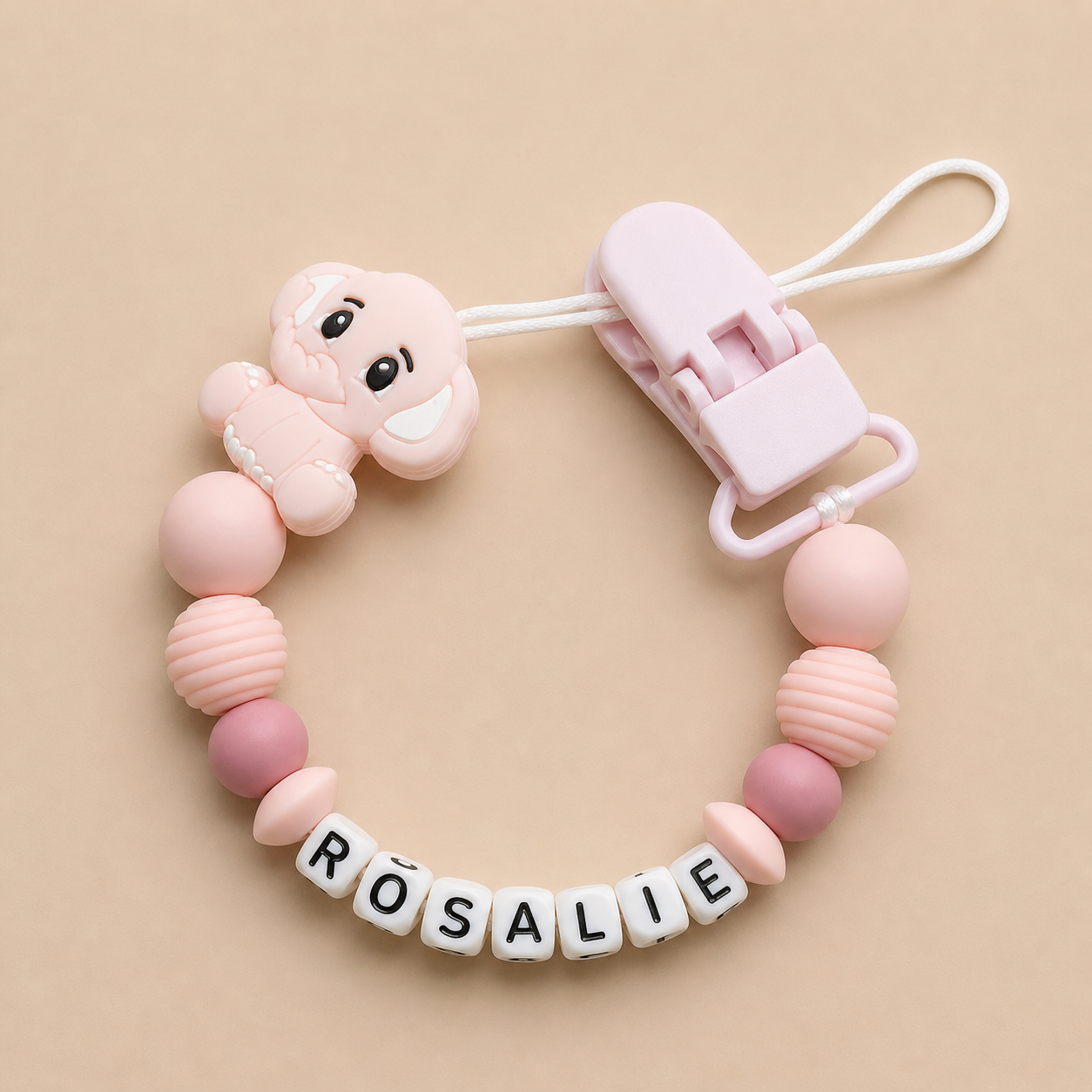 Pink baby dummy clip with 'ROSALIE' on a beige background
