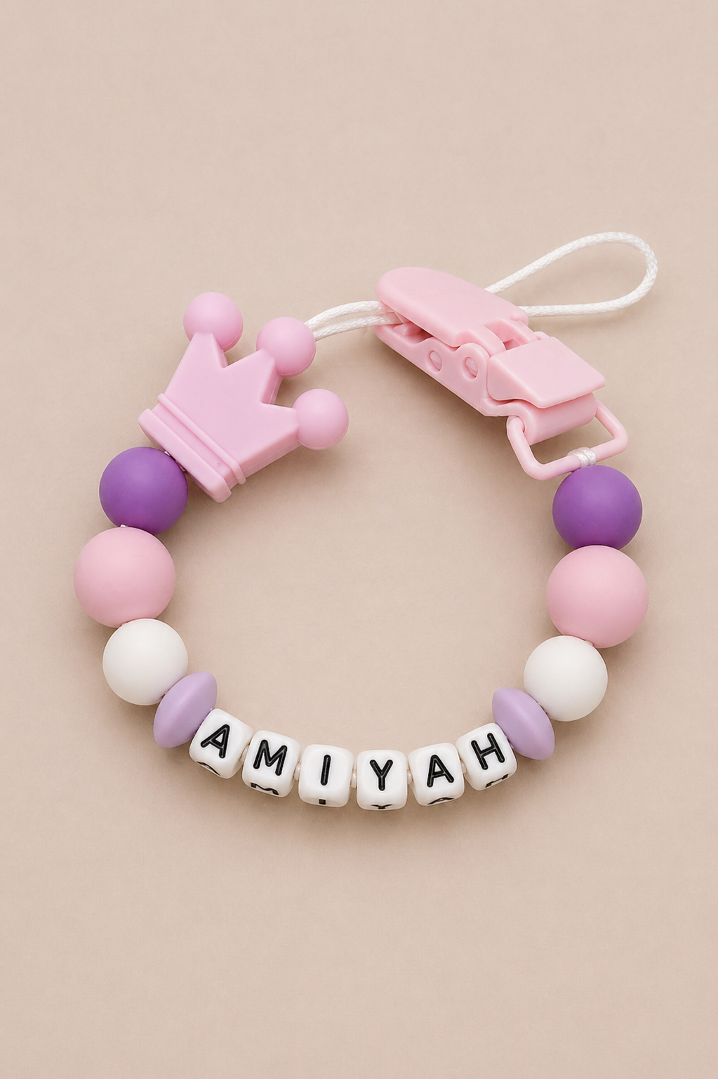 Baby teether with colorful beads and a name tag on a beige background